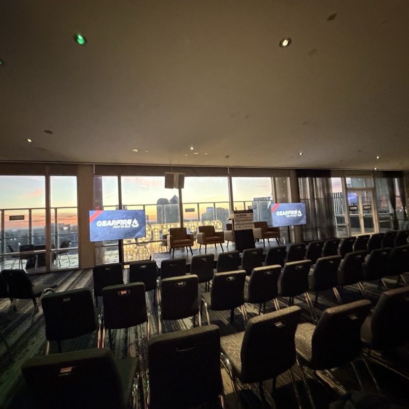 Sunrise over the Dallas skyline seen through an empty session room, with sponsor screens flanking the stage