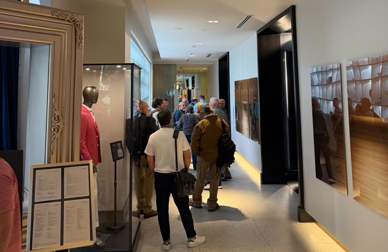Attendees filing through a hotel corridor lined with framed photography