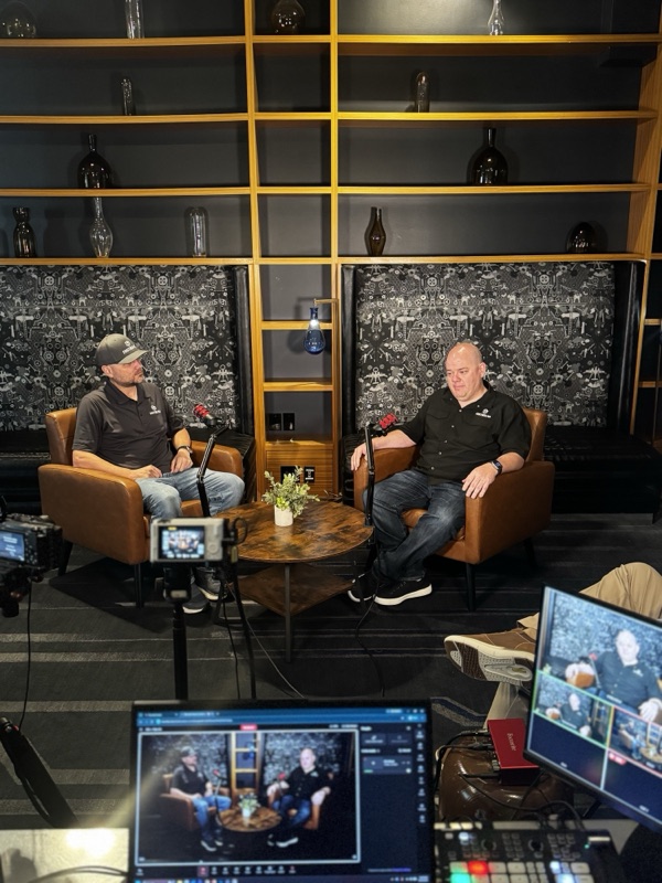 FastBound COO Jarad Haselton and CEO Jason Smith seated on the livestream set, with production monitors in the foreground