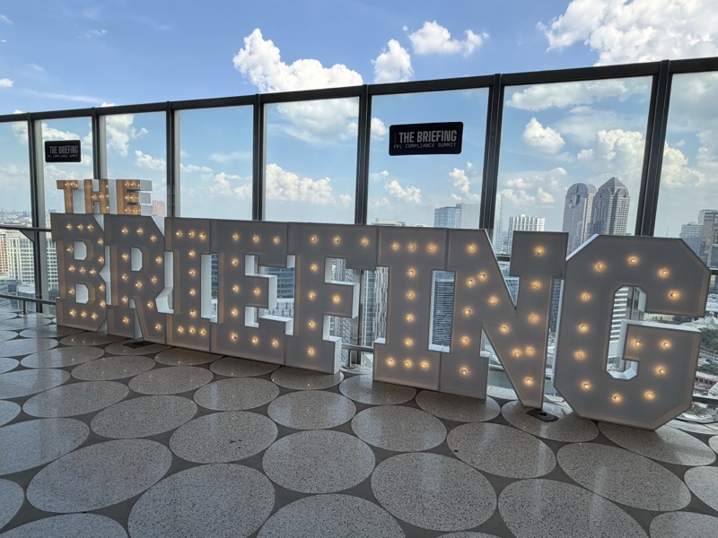 The Briefing marquee by day with the Dallas skyline behind