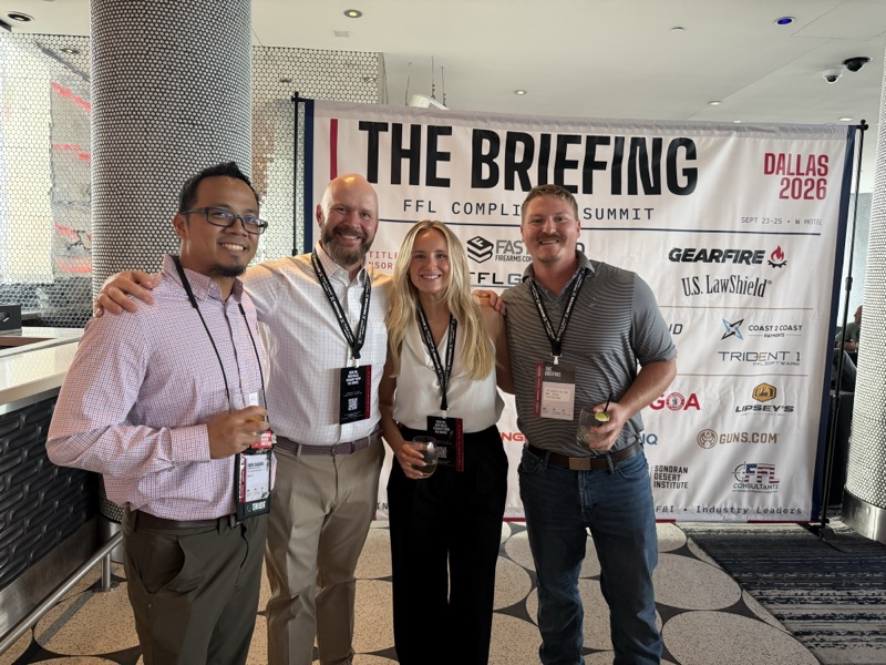 Four guests posing at The Briefing backdrop during the welcome reception